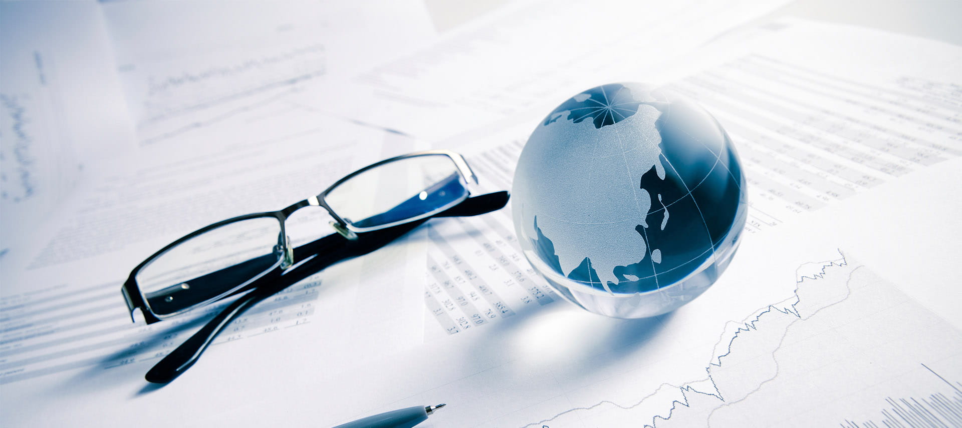 Glasses and mini globe sitting on top of papers.