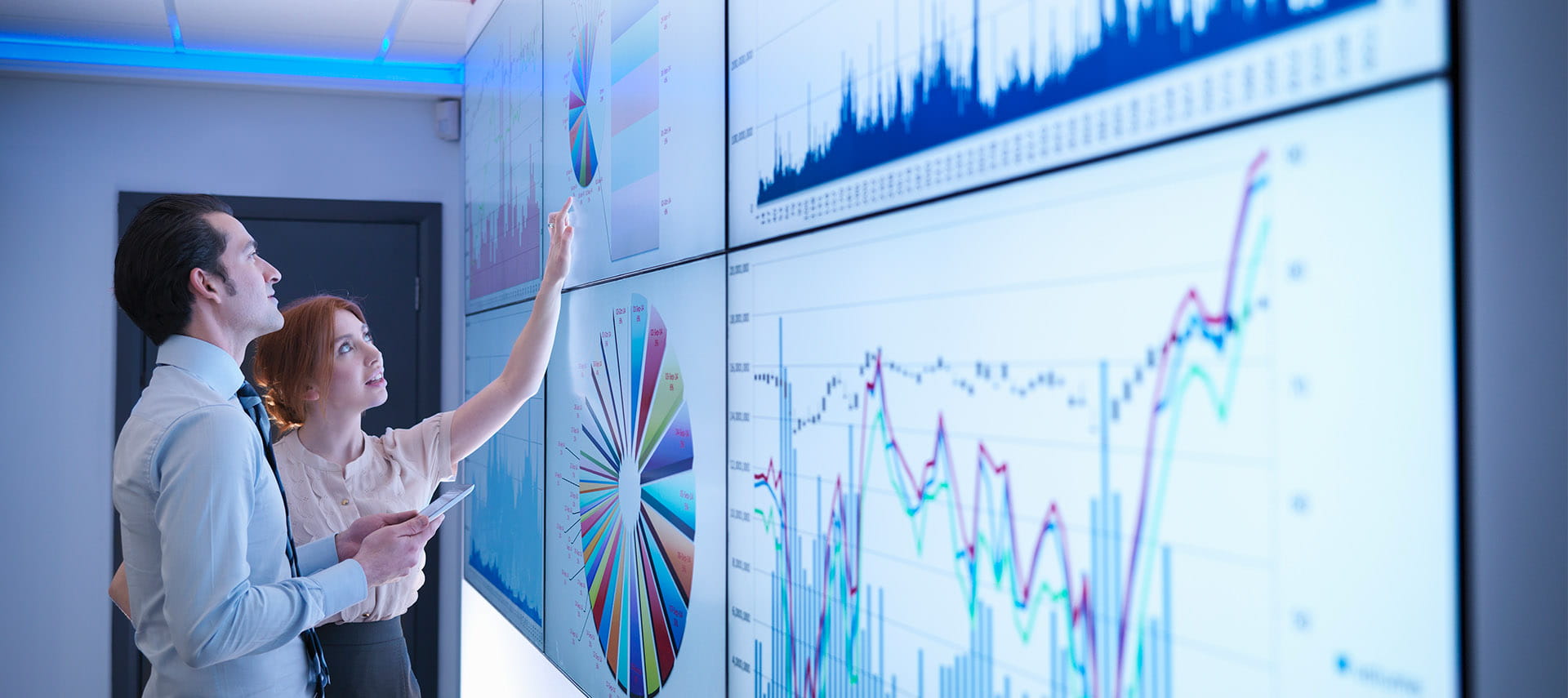 Business colleagues studying graphs on screen in meeting room.