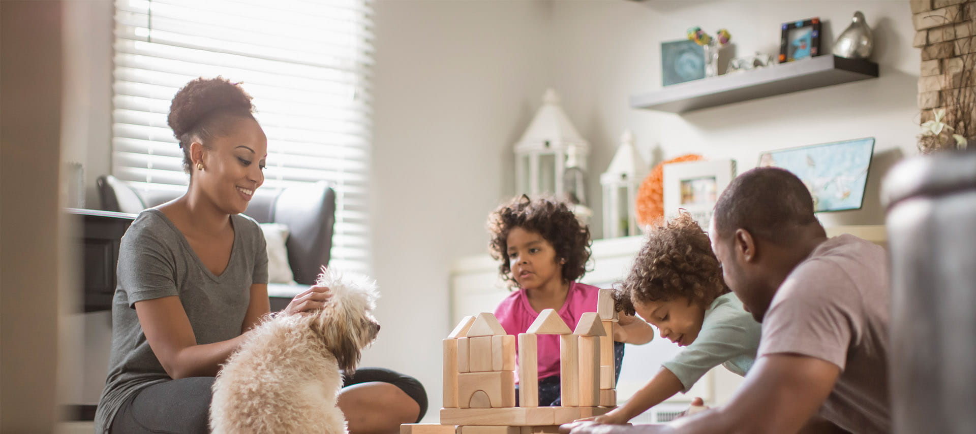 Family and dog in the living room playing with building blocks.