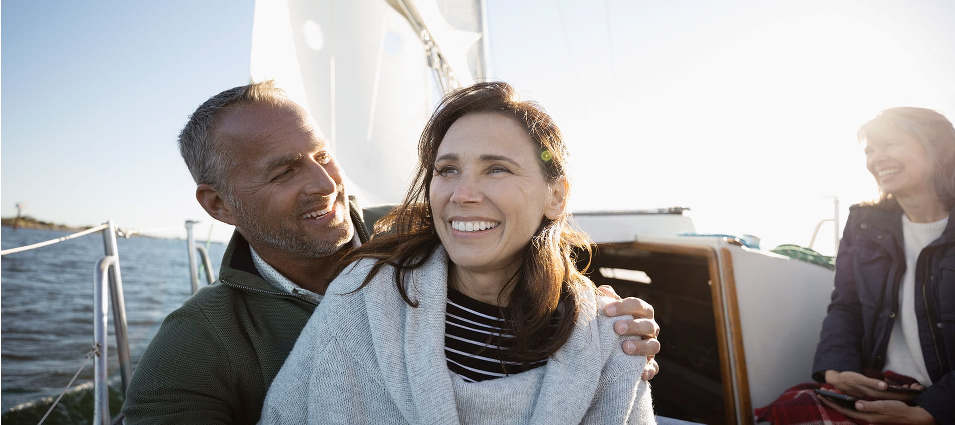 Smiling couple on a sailboat with friends.