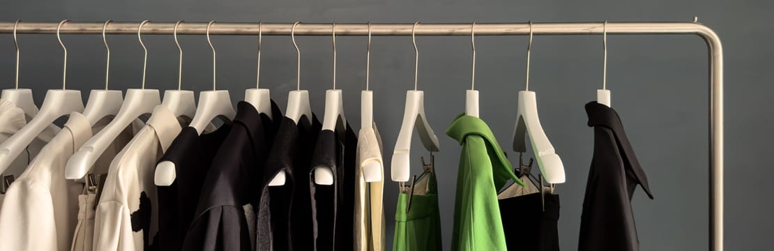 Clothing rack with neutral and green garments, illustrating clothing rental as a sustainable, chic and cost-effective option for your wardrobe.